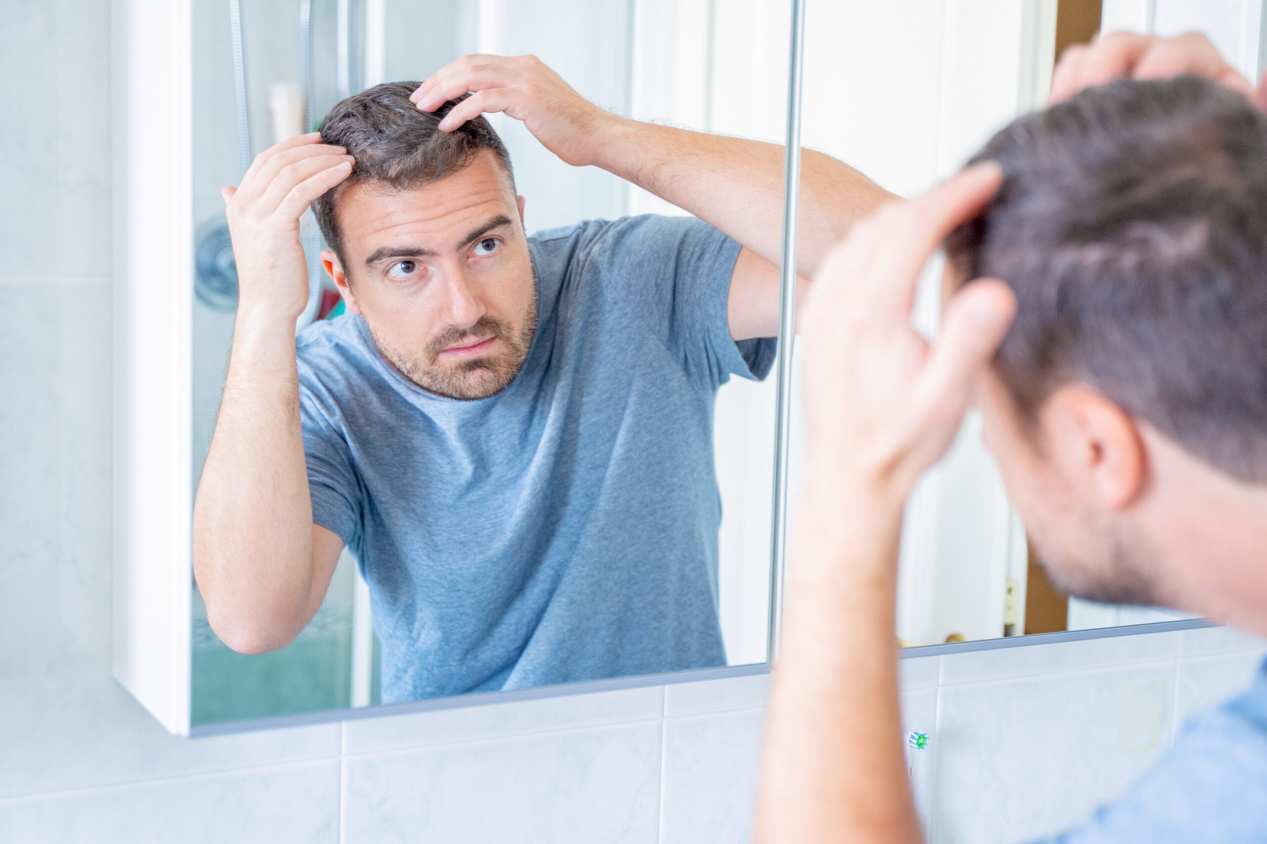 Mężczyzna przegląda się w lustrze i obserwuje stan włosówŹródło: https://stock.adobe.com/pl/images/worried-guy-checking-hair-loss-problem-in-the-morning/465959127?asset_id=465959127