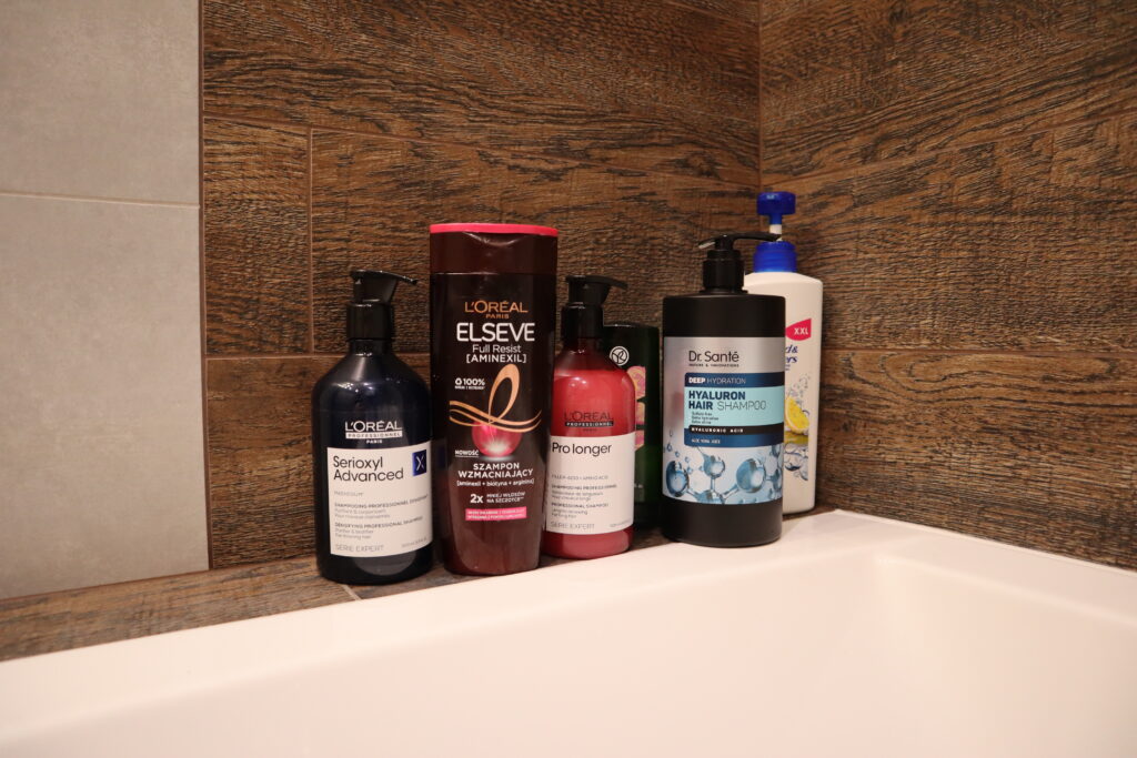 Szampon L'Oréal Paris Professionnel Serioxyl Advanced i inne kosmetyki do włosów stojące w łazience przy wannie