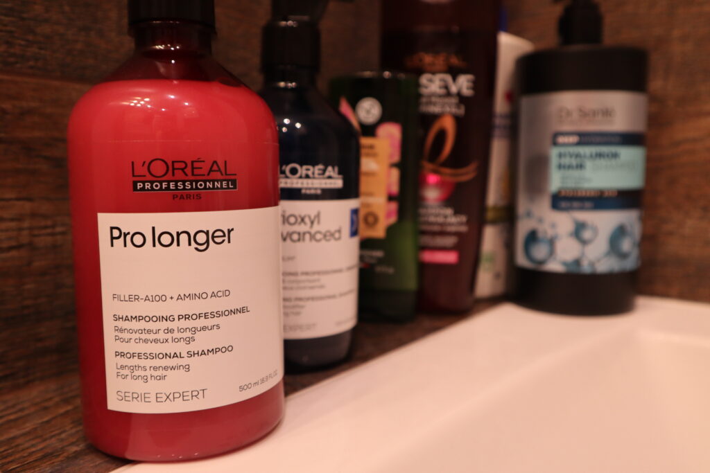 szampon L'Oréal Professionnel Pro Longer stojący w łazience z innymi kosmetykami do włosów