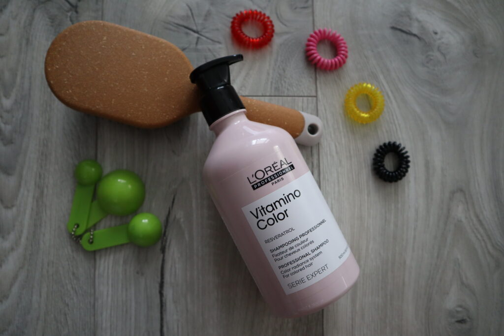 Szampon L'Oréal Professionnel Vitamino Color leżący wokół akcesoriów do włosów