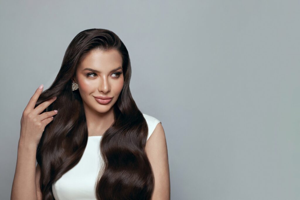 Kobieta z uśmiechem na twarzy prezentuje długie, ciemne włosy w kolorze espresso martini