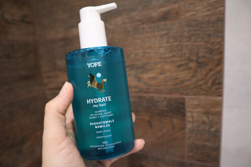 Dłoń trzymająca przy prysznicu szampon nawilżający do włosów Yope Hydrate My Hair