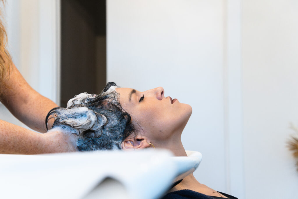 Fryzjerka myje klientce włosy w salonie fryzjerskim