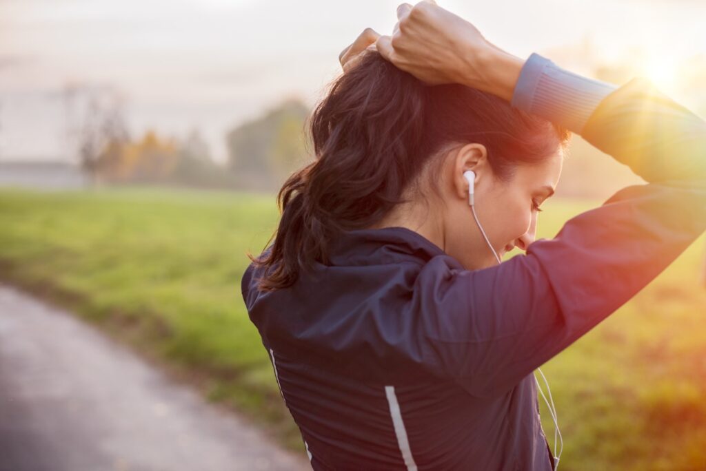 Kobieta poprawia kucyk na włosach podczas biegania na dworze wiosną