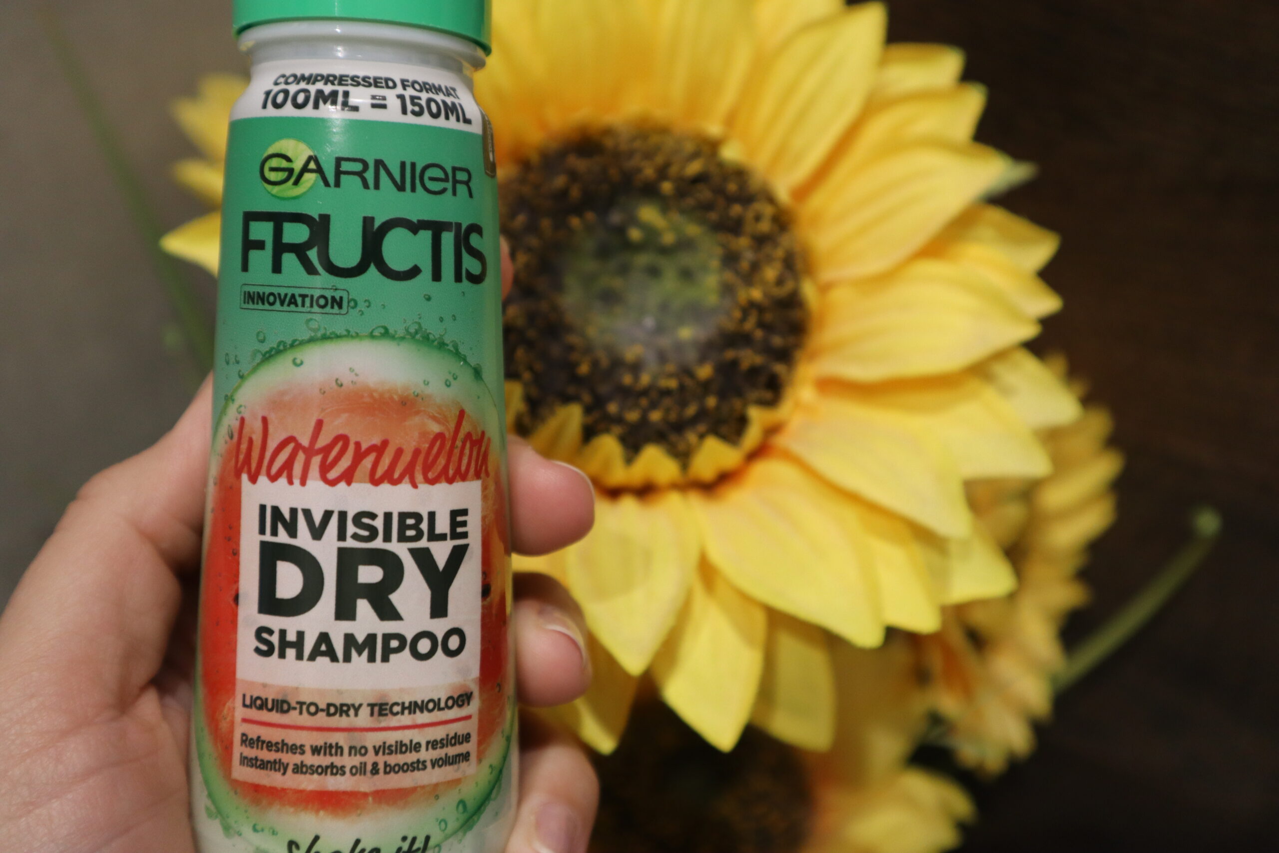 Suchy szampon do włosów Garnier Fructis Watermelon Invisible suchy szampon na tle sztucznego słonecznika