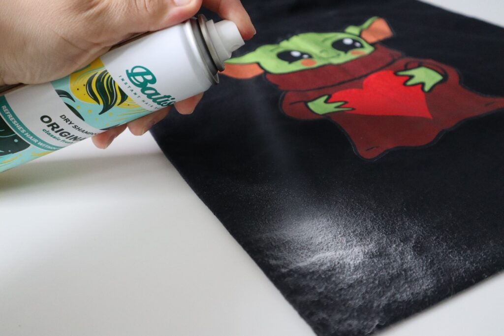 Suchy szampon Batiste original podczas aplikacji na czarnym materiale