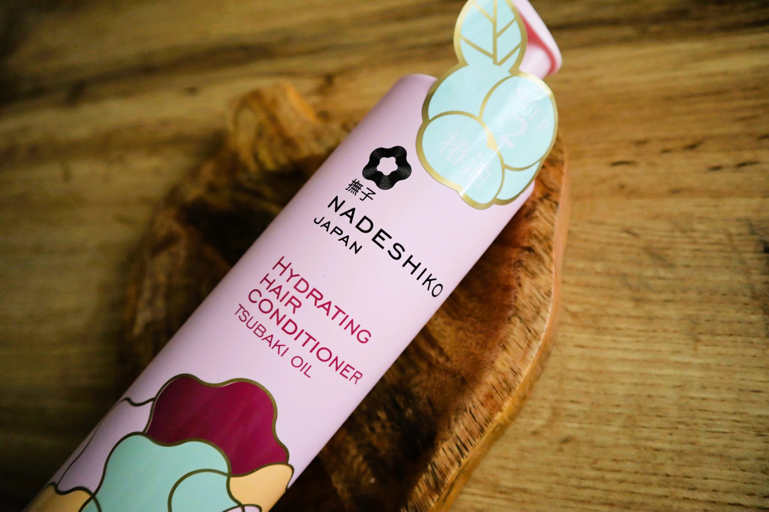 Nadeshiko odżywka nawilżająca do włosów leżąca na drewnianej misce dekoracyjnej na drewnianym sole