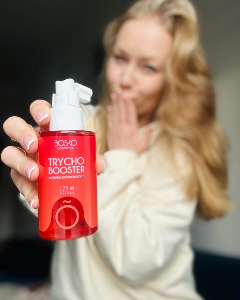 Kobieta trzymająca w dłoni wcierkę Bosko Trychobooster. Źródło: https://www.facebook.com/boskocosmetics/