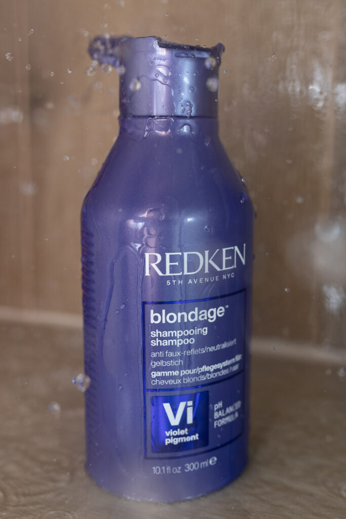 Butelka szamponu Redken Color Extend Blondage pod prysznicem