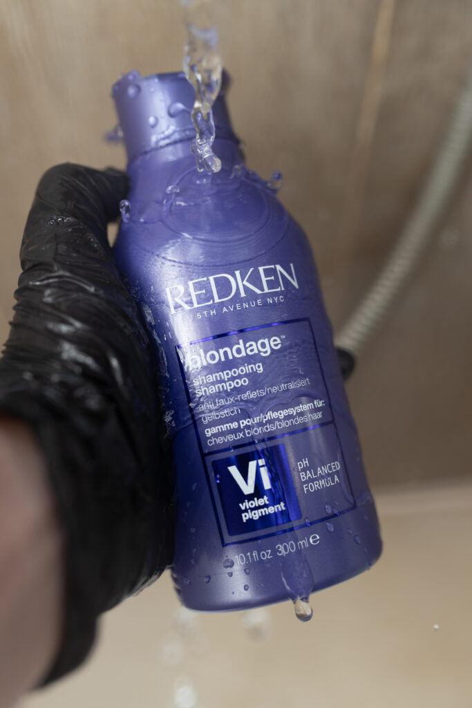 Kobieca dłoń trzymająca szampon Redken Color Extend Blondage