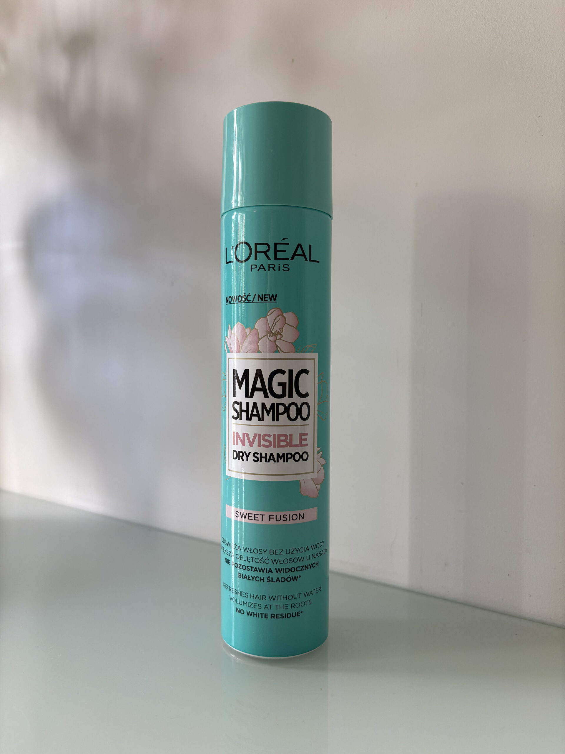 Suchy szampon do włosów L'Oréal Paris Sweet Fusion na tle szarej ściany z cieniem