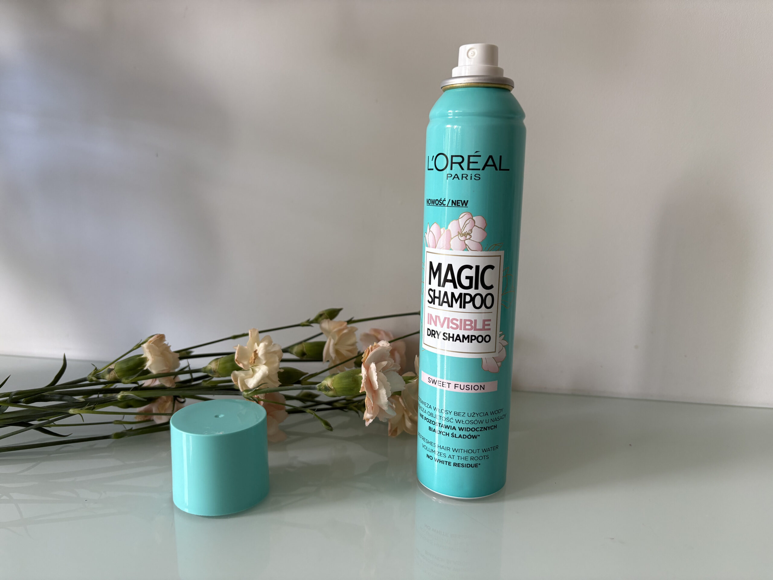 Suchy szampon do włosów L'Oréal Paris Sweet Fusion, w tle suszone kwiaty