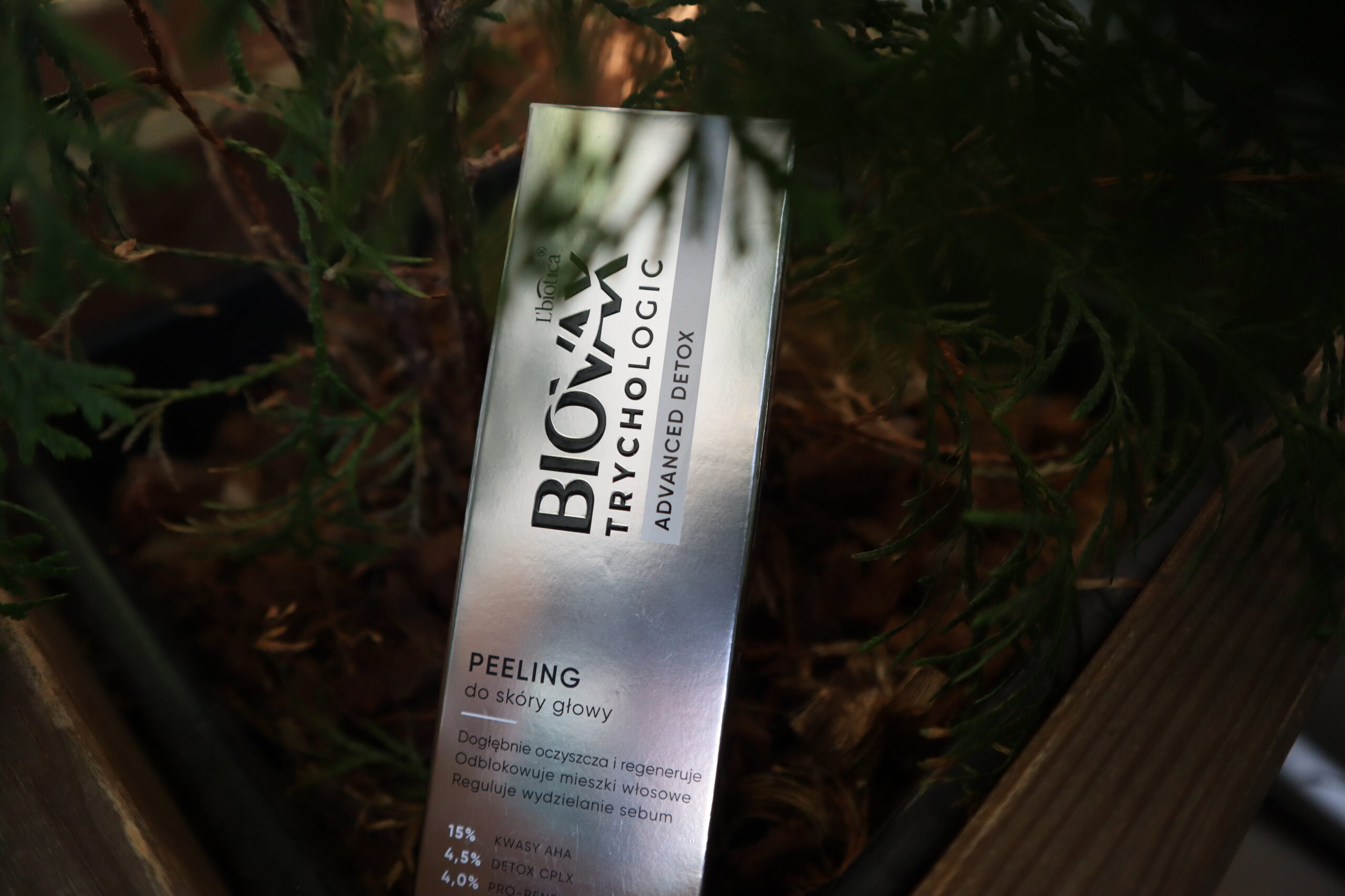 Opakowanie peelingu do skóry głowy L'biotica Biovax Trychologic Advanced Detox na ciemnym tle roślin