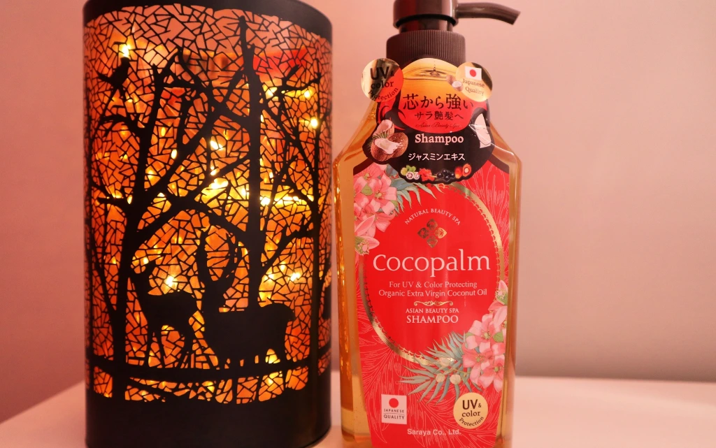  Nabłyszczający szampon do włosów Cocopalm obok jesiennej, dekoracyjnej lampki 
