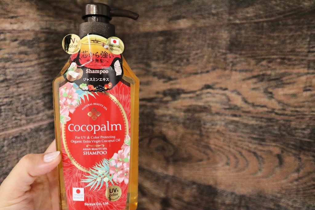 Nabłyszczający szampon do włosów Cocopalm na tle brązowych płytek łazienkowych