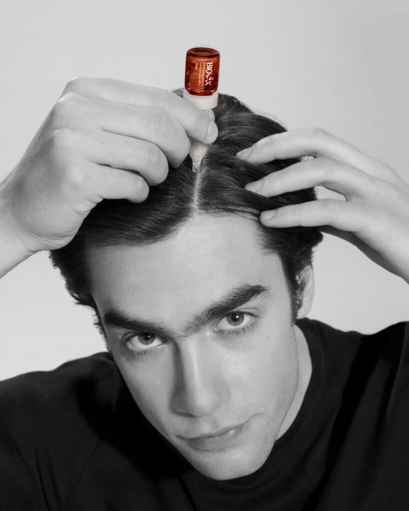 Mężczyzna aplikujący na skórę głowy ampułkę Biovax Men TrychoLogic. Źródło: https://www.facebook.com/lbiotica/