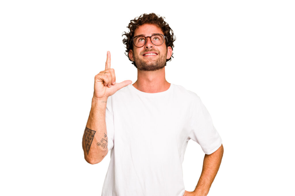 Mężczyzna z drobnymi lokami na włosach i w białej koszulce wskazuje palec ku górze