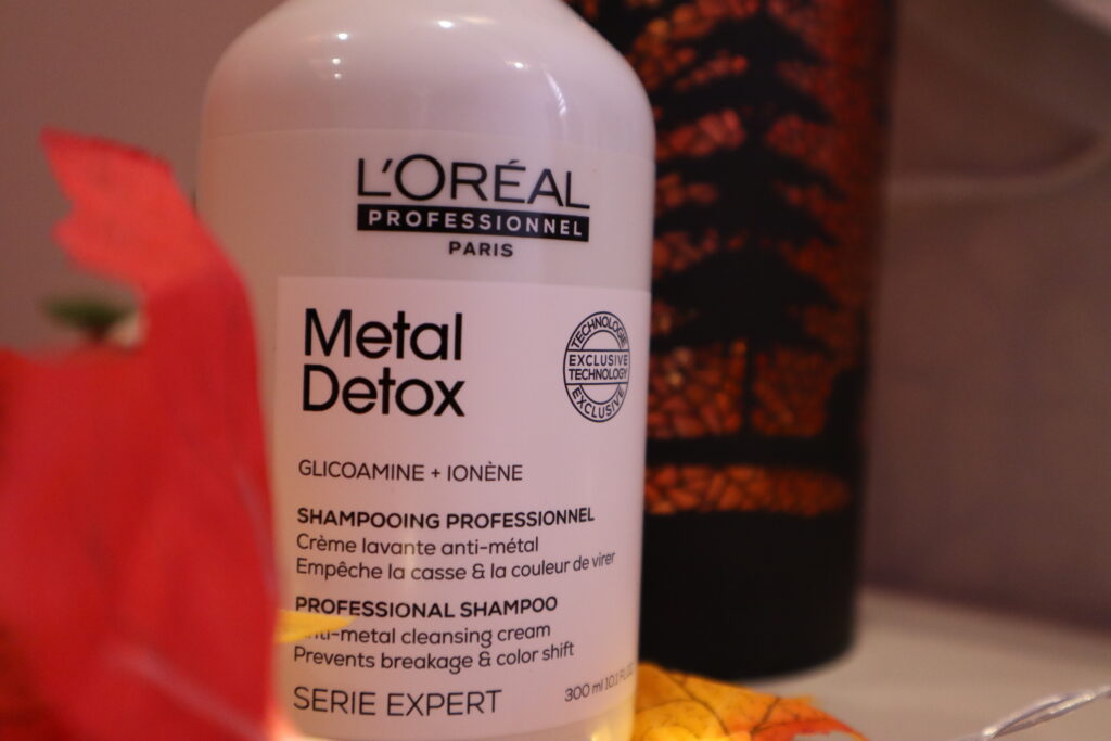Szampon oczyszczający włosy L'Oréal Professionnel Metal Detox na tle jesiennych dekoracji