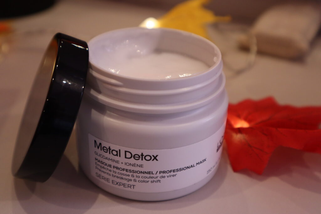 Otworzone opakowanie maski do włosów po zabiegu farbowania Metal DetoxL'Oreal Professionnel na tle jesiennych lampek ozdobnych