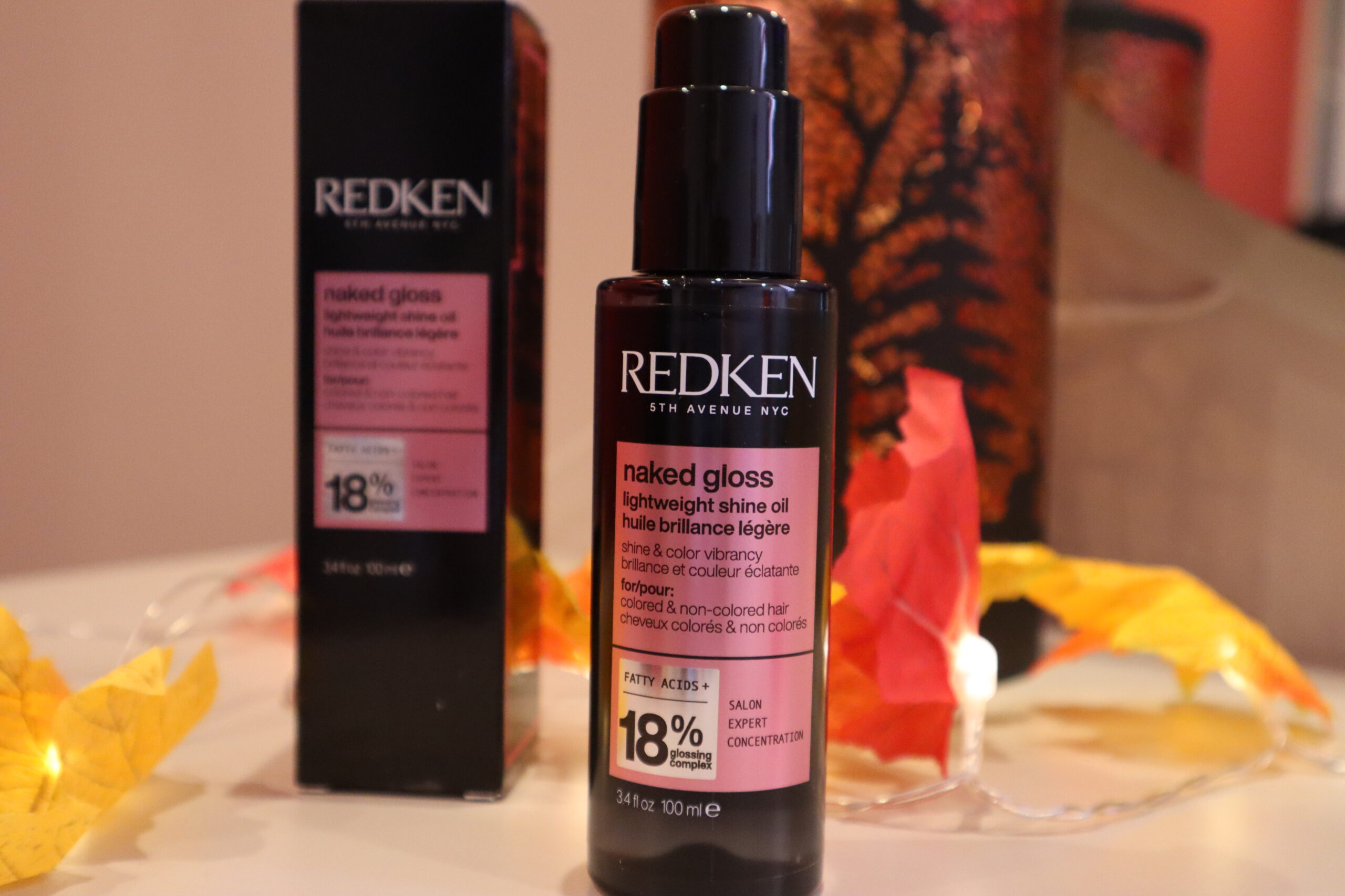 Olejek nabłyszczający do włosów farbowanych REDKEN Naked Gloss na tle jesiennych dekoracji