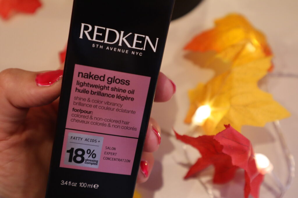 Olejek nabłyszczający do włosów farbowanych REDKEN Naked Gloss na tle jesiennych lampek