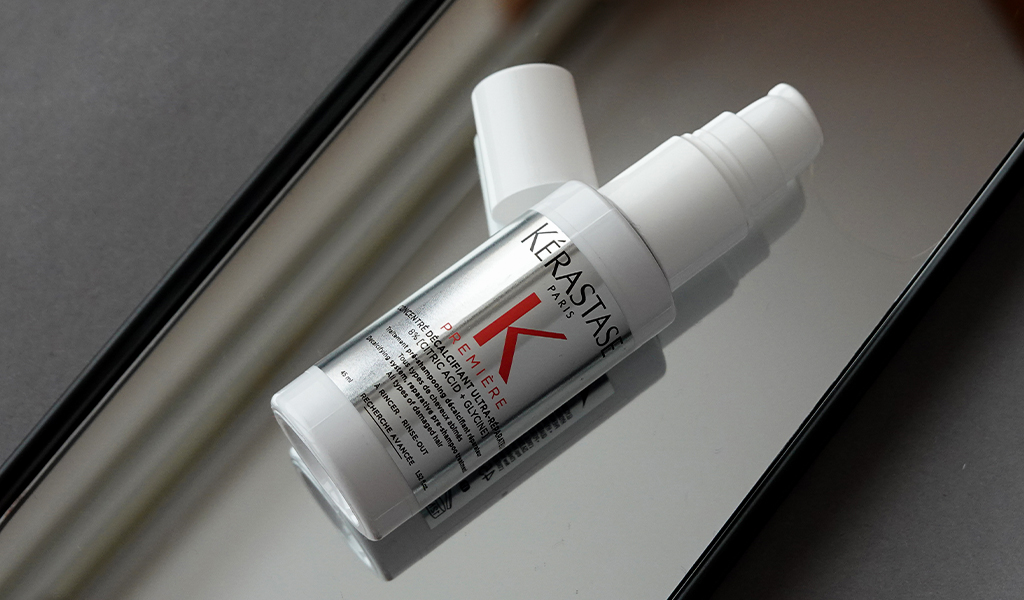 Kerastase Première 'Ultra naprawczy' koncentrat dekalcyfikujący przed kąpielą leżący na lustrzanej powierzchni - zdjęcie.