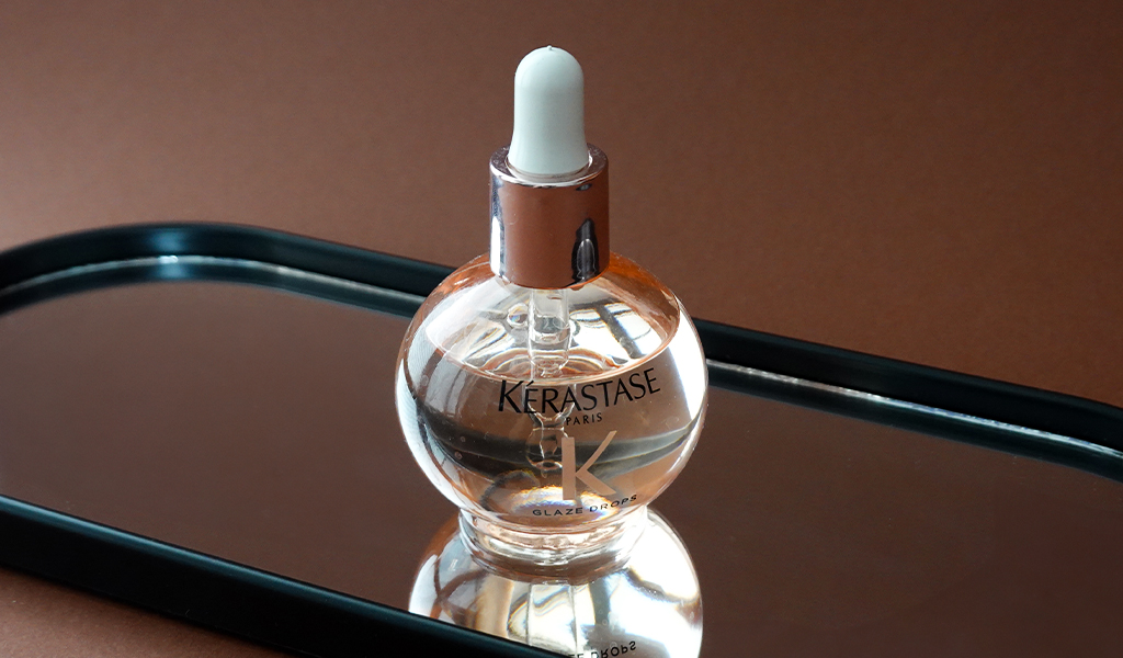 Olejek do włosów Kerastase Gloss Absolu leżący na lustrzanej powierzchni - tytułowa.