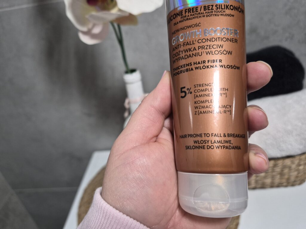 Kobieca dłoń trzyma odżywkę do wypadających włosów L’Oreal Paris Elseve Growth Booster