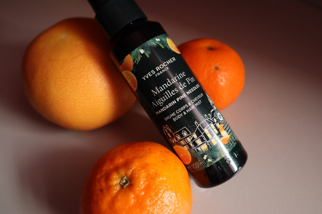 Mgiełka do ciała i włosów leśna mandarynka Yves Rocher na tle pomarańczy i mandarynek