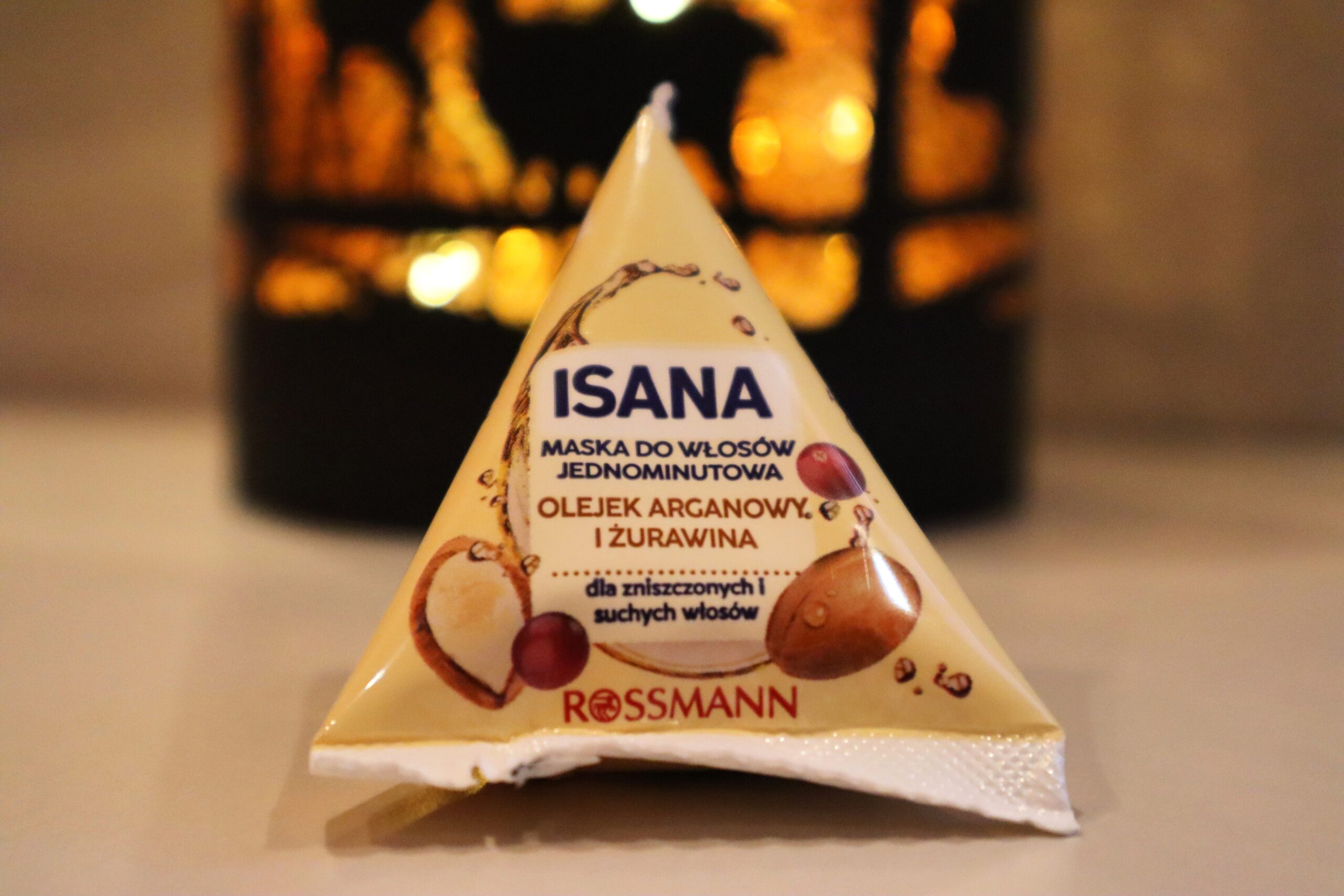 Żółty trójkącik Isana maska do włosów jednominutowa olejek arganowy i żurawina na tle świecącej lampki