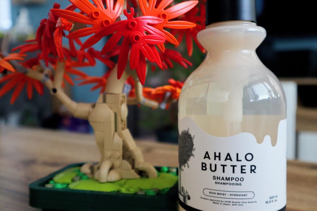 Butelka Ahalo Butter Nawilżająco-odżywczy szampon do włosów w tle drzewko z klocków LEGO
