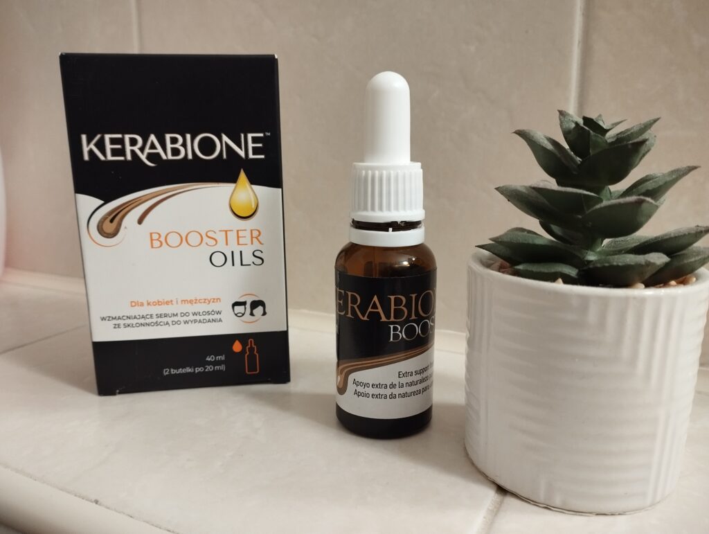 Serum przeciw wypadaniu włosów Kerabione Booster Oils wyjęte z opakowania, obok papierowy kartonik i kwiatek