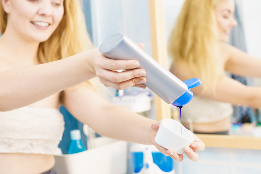 Kobieta aplikuje szampon koloryzujący, który redukuje żółte tony