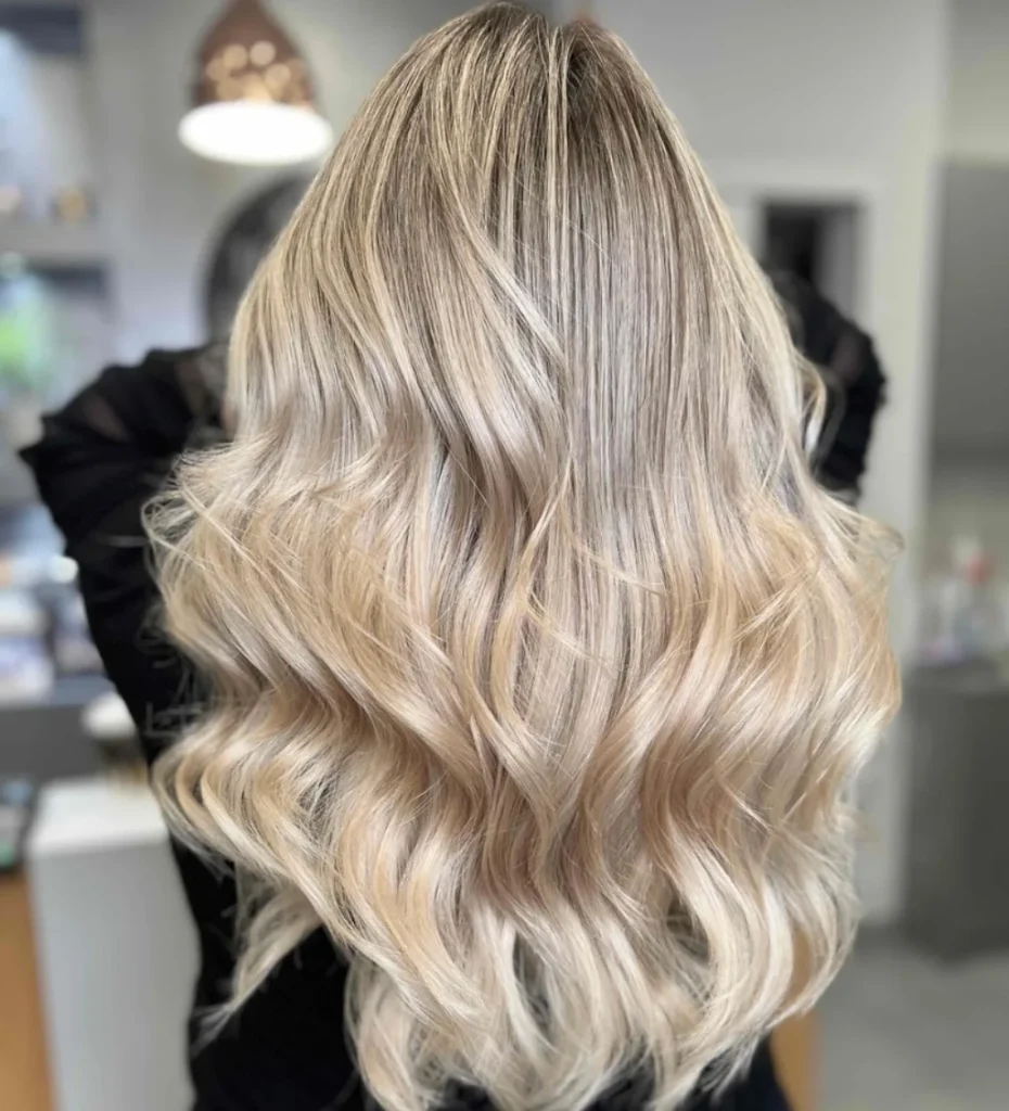 Kobieta odwrócona plecami prezentuje efekt air touch bride blond na długich włosach