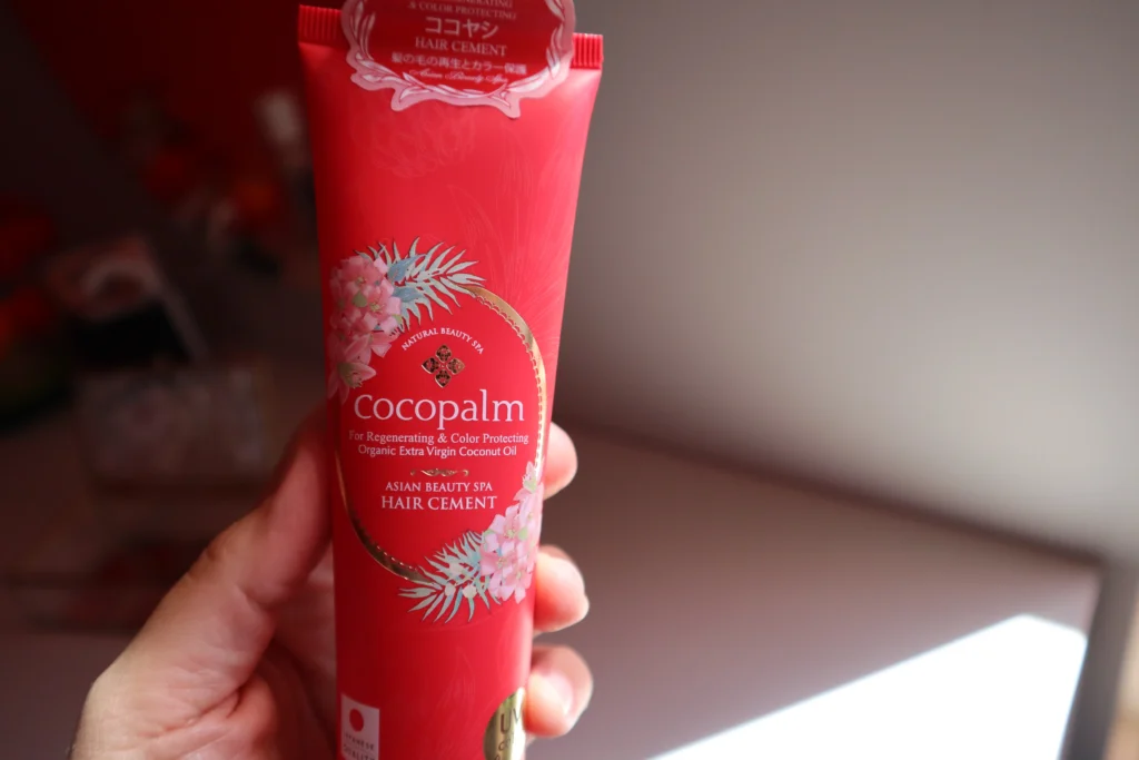 Odbudowujący cement do włosów Cocopalm trzymany w kobiecej dłoni