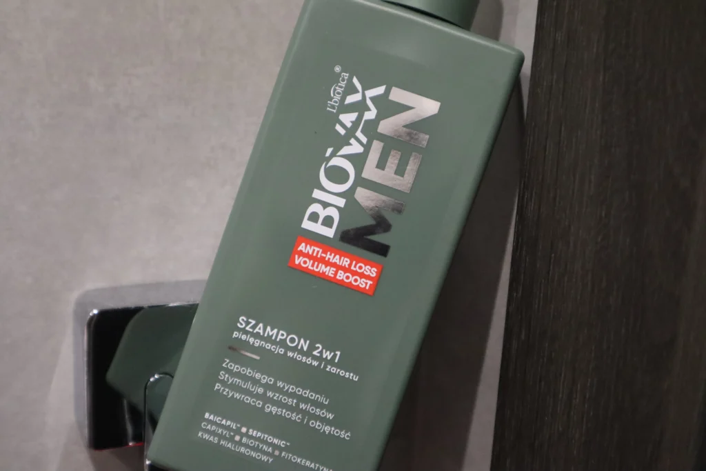 Szampon na wypadanie włosów Biovax Men oparty o futrynę drzwi