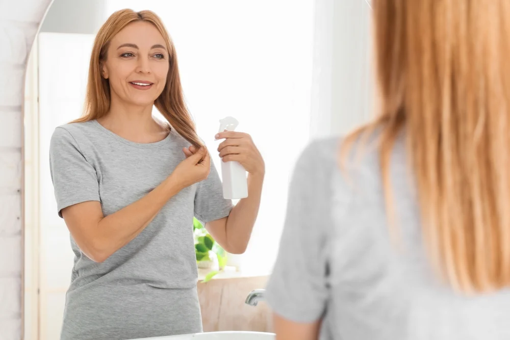 Kobieta w okresie menopauzy aplikuje spray na wzmocnienie włosów