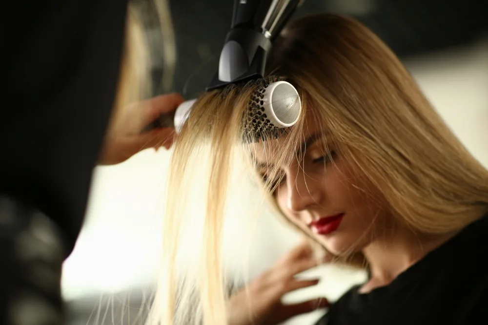 Długowłosa blondynka u fryzjera stylizuje grzywkę