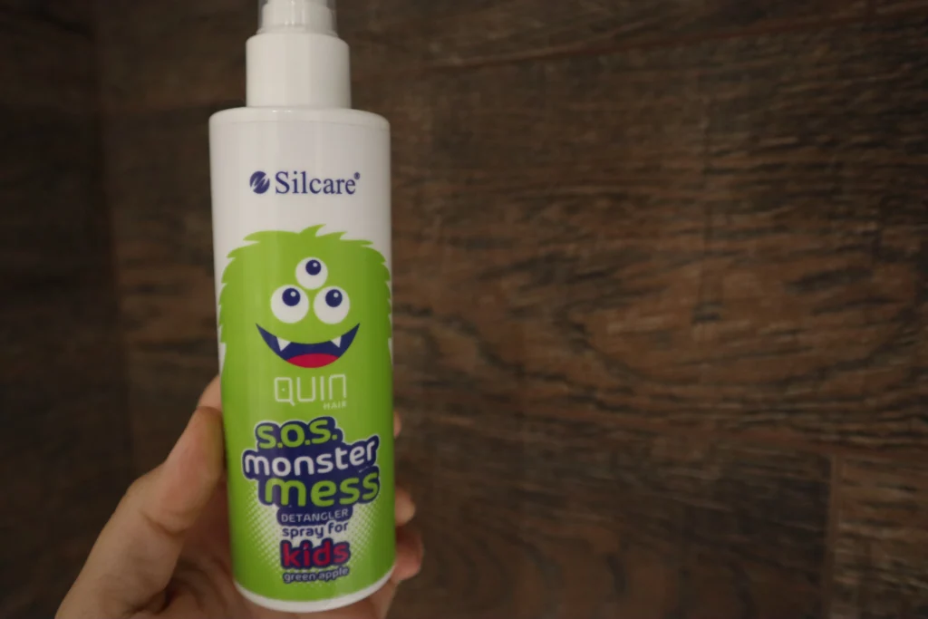 Spray do rozczesywania włosów Silcare Quin Hair S.O.S Monster Mess na tle brązowych płytek w łazience