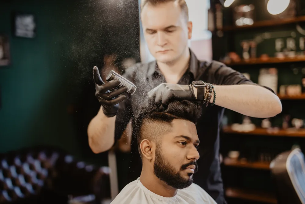 Fryzjer w salonie używa pudru do włosów do stylizacji męskiej fryzury
