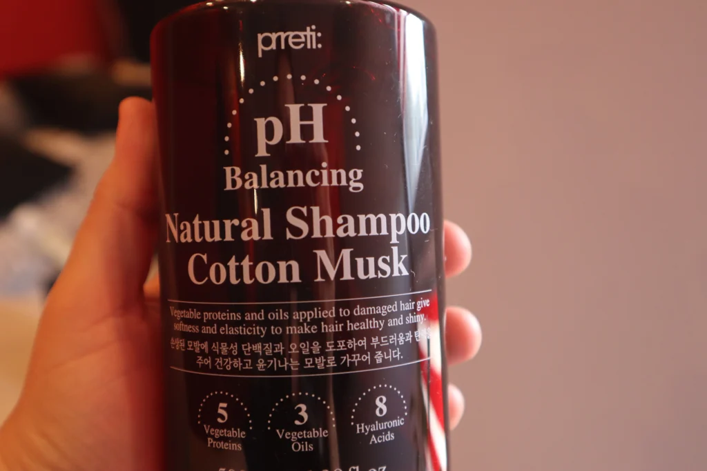 Zbliżenie na Prreti Cotton Musk szampon do włosów zniszczonych w kobiecej dłoni