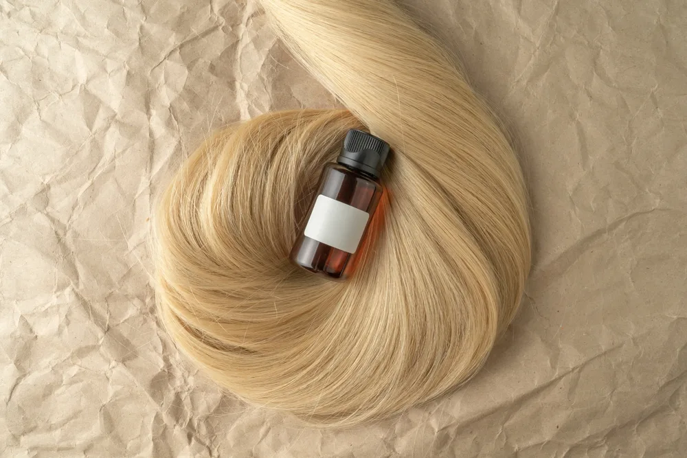 Buteleczka serum silikonowego na pęku blond włosów